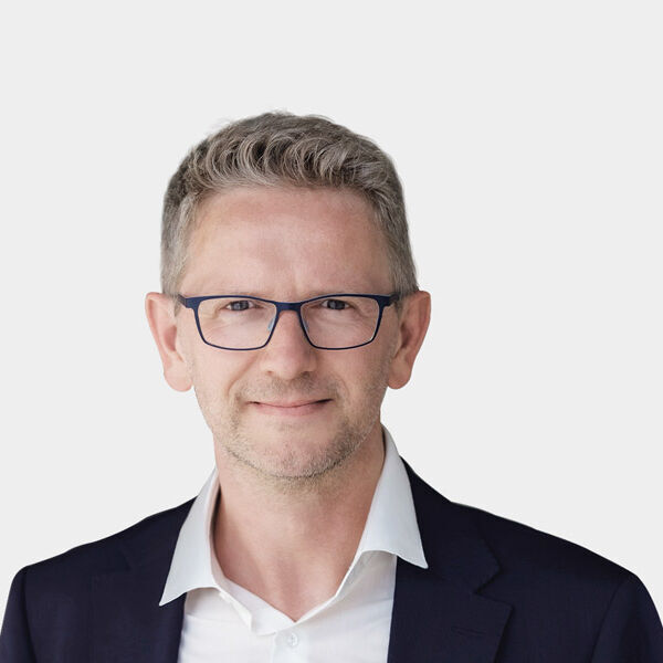 Portraitfoto von Bjoern Sixt vor grauem Hintergrund