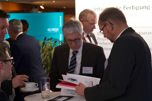 ROI 2. Fachkongress Industrie 4.0 Zwei Maenner unterhalten sich und sehen in ein Broschuere