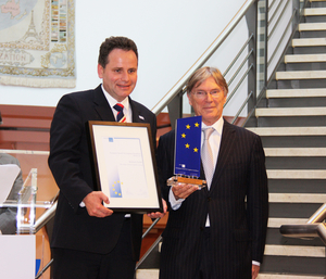 Foto mit Zwei Männern, die den Logistikpreis in der Hand halten