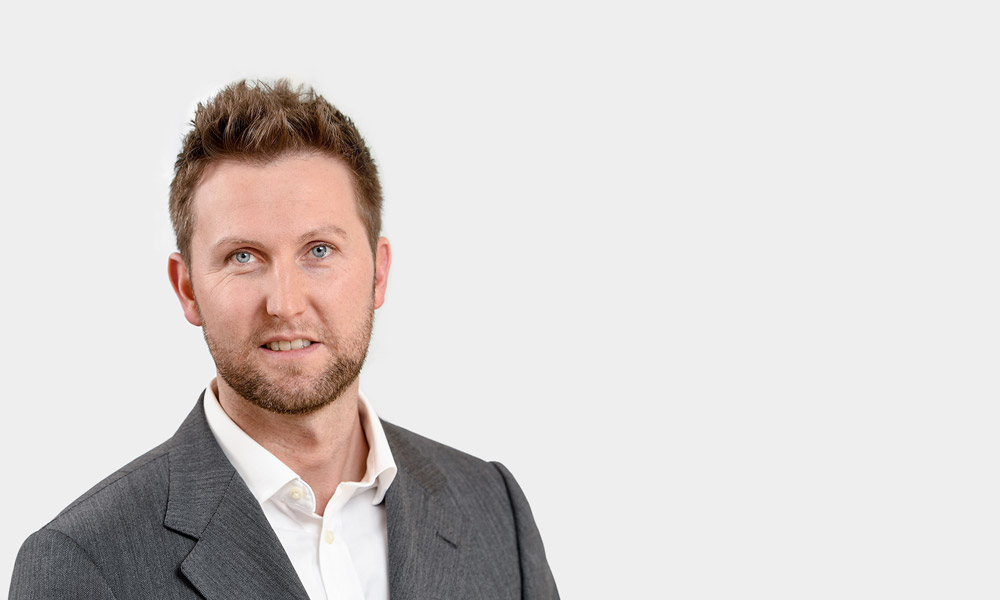 Robert Micheli, Senior Consultant Portraetfoto von Robert Micheli vor grauem Hintergrund