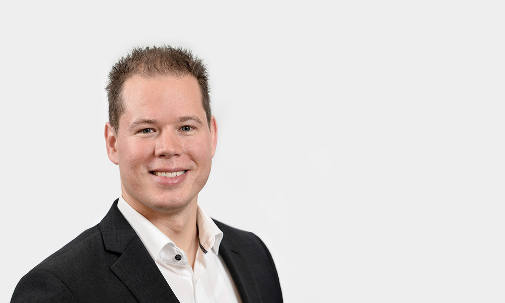 Marcel Sambale, Consultant Portraetfoto von Marcel Sambale vor grauem Hintergrund